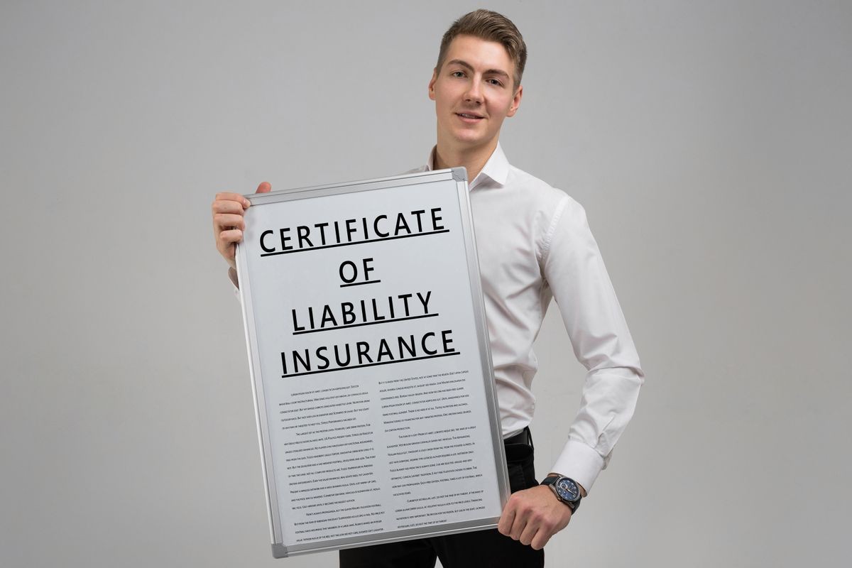 young man holding a certificate of liability insurance isolated on a light background