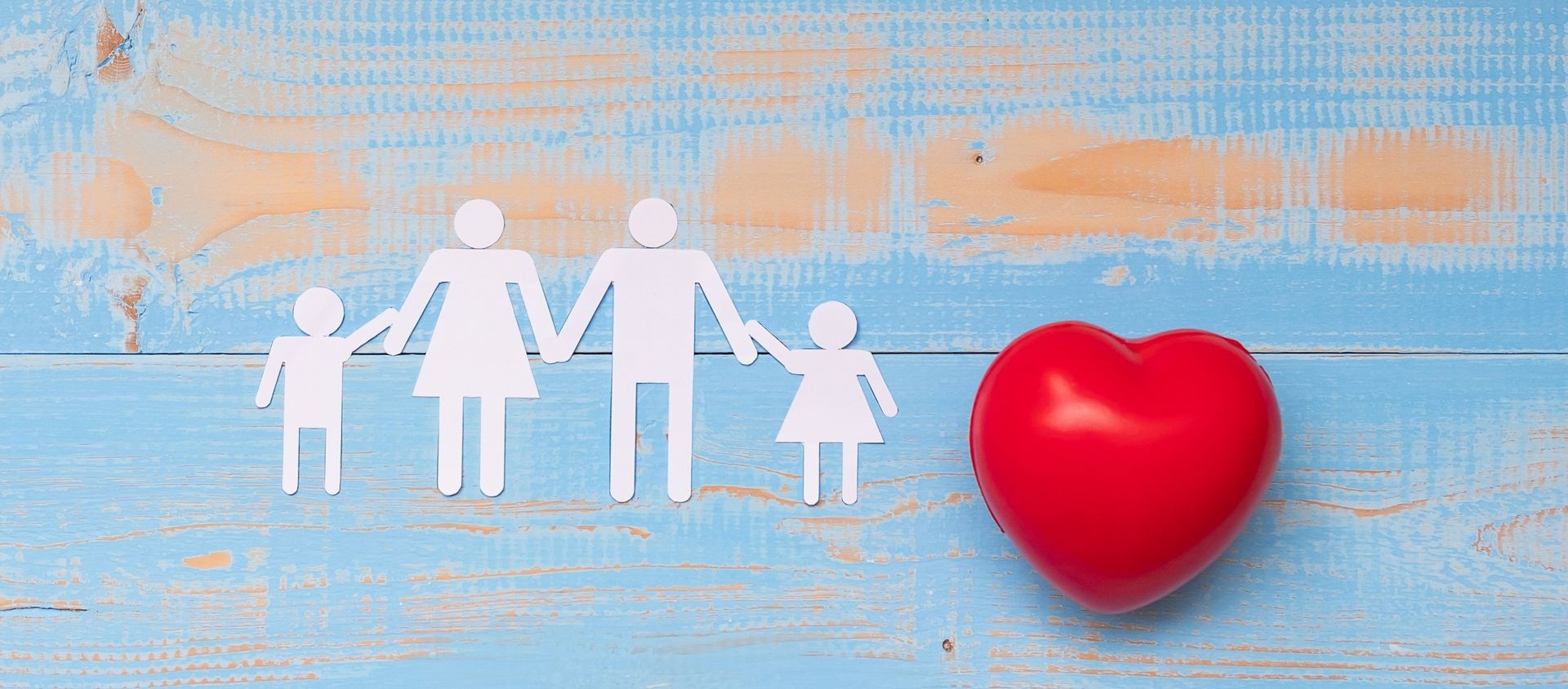 Red heart shape with Family paper on blue pastel color wooden background. Healthcare and Insurance concept